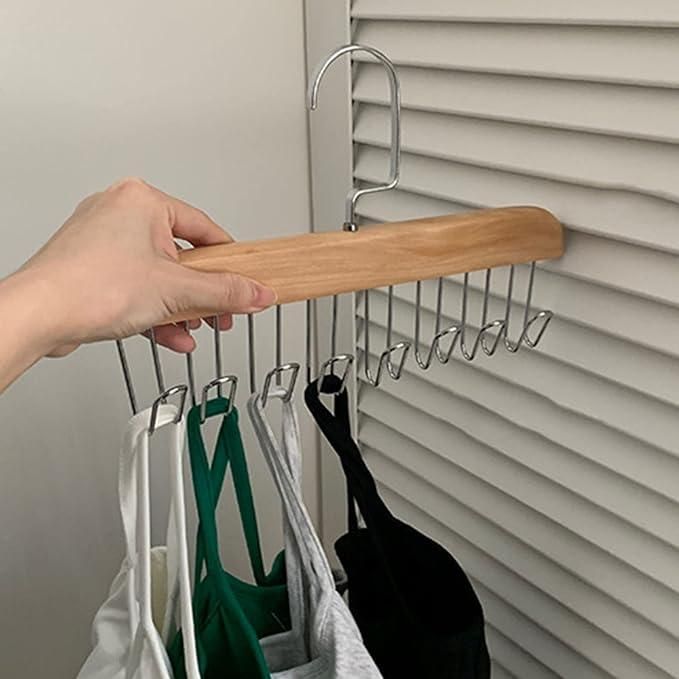 A hand lifting one wooden accessory organiser, loaded with a bag and a scarf on its loops, off a wardrobe rail